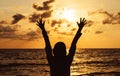 Silhouette of Happy woman standing with hands raise up while sunset at sea,Light flare,Enjoys of resting time,Freedom concept Royalty Free Stock Photo