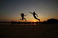 Silhouette of a happy young couple having fun outdoors, man and woman jumping on the beach by the river, lake on sunset Royalty Free Stock Photo