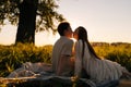 Silhouette of happy young couple sitting hugging and kissing on green field having picnic date in field with green grass Royalty Free Stock Photo