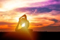 Silhouette of healthy woman practicing yoga meditation during on background city with sky and sunset Royalty Free Stock Photo