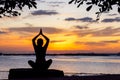 Silhouette healthy woman yoga balance body exercising vital meditate and practicing on the rock outdoor in the beach at sunset. Royalty Free Stock Photo