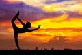 Silhouette of healthy woman practicing yoga meditation during on background city with sky and sunset Royalty Free Stock Photo