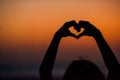 Silhouette of heart made by kids hand at sunset