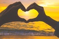 Silhouette heart shape with hand at the beach at sunset. Royalty Free Stock Photo