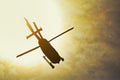 Silhouette of a helicopter flying in the rays of the setting sun