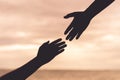 Silhouette helping hands on blurred sea and sky background Royalty Free Stock Photo