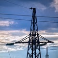 Silhouette of a high-voltage power line tower against cloudy sky in the evening Royalty Free Stock Photo