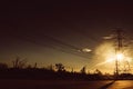 Silhouette of high voltage tower with electrical wires on sunset background. View through the grass. Power line support in a field Royalty Free Stock Photo