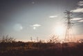 Silhouette of high voltage tower with electrical wires on sunset background. View through the grass. Power line support in a field Royalty Free Stock Photo