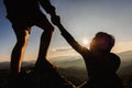 Silhouette of hiker helping each other hike up a mountain at sunset. People helping and, team work concept