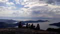 Silhouette of hikers on top of the mountain watching the wonderful view of the sea bay