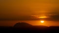 Silhouette of hills against beautiful golden hour sunset amidst a streak of clouds Royalty Free Stock Photo