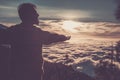 Silhouette of hipster man or carefree traveler with arms outstretched admiring scenic beautiful nature of cloudy sky during sunset Royalty Free Stock Photo