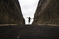 Silhouette on the horizon of young happy and active woman running and jumping excited on road between mountain cliffs feeling free