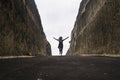 Silhouette on the horizon of young happy and active woman running and jumping excited on road between mountain cliffs feeling free