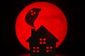 The silhouette of a Horror haunted house and Ghost spirit. There`s a red full moon in the background. Halloween horror concept