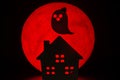 The silhouette of a Horror haunted house and Ghost spirit. There`s a red full moon in the background. Halloween horror concept