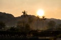 Silhouette of hotel swimming pool, palm trees, umbrellas and chairs. Tropical resort at sunrise, soft focus picture