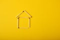 Silhouette of a house made of matches on a yellow background Royalty Free Stock Photo