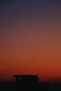 Silhouette houses in a distance under orange evening sky, vertical shot