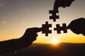 Silhouette of human hands connected jigsaw puzzle at sunset, Joint Business Concepts
