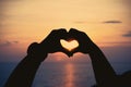 Silhouette human hands in heart symbol shaped at sunset