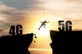 Silhouette Human jumping from 4G cliff to 5G cliff with cloud sky and sunset. Technology change and transformation concept Royalty Free Stock Photo