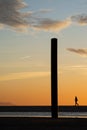 Silhouette of human walking in beach behind wooden fence during sunset Royalty Free Stock Photo