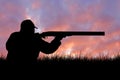 A hunter with a gun in his hands in hunting clothes in the autumn forest in search of a trophy Royalty Free Stock Photo