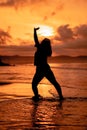 silhouette image of an Asian woman doing ballet movements very flexibly on the beach