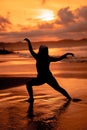 silhouette image of an Asian woman doing ballet movements very flexibly on the beach