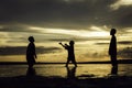 Silhouette image concept of young boys playing at the beach with beautiful sunrise sunset background. Royalty Free Stock Photo