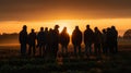 Silhouette image of a group of farmers standing together in a field at sunset
