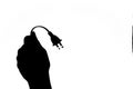 Silhouette image of a hand holding up a electric power cable and plug Royalty Free Stock Photo