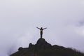 Silhouette image of man standing with arms stretched on a rock With clouds floating in the front Royalty Free Stock Photo