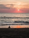 Silhouette of an indefinite person in lotus position on a sea sandy beach during a beautiful sunset. Meditation during sunset. A Royalty Free Stock Photo