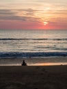 Silhouette of an indefinite person in lotus position on a sea sandy beach during a beautiful sunset. Meditation during sunset. A