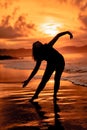 the silhouette of an Indonesian teenager dancing very flexibly with the crashing waves on the beach