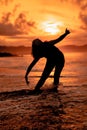 the silhouette of an Indonesian teenager dancing very flexibly with the crashing waves on the beach