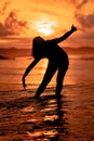 the silhouette of an Indonesian teenager dancing very flexibly with the crashing waves on the beach