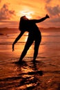 the silhouette of an Indonesian teenager dancing very flexibly with the crashing waves on the beach