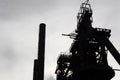 Silhouette of industrial site with smokestacks against a gray sky,