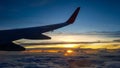 Silhouette of jet plane`s wing over the clouds at high altitude when sunset. Royalty Free Stock Photo