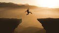 Silhouette jumping cliff sunset mountain. Courageous Man Jump Between Two Cliffs. Business Goals achievement Royalty Free Stock Photo