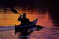 silhouette of a kayaker at sunset, water reflecting colors Royalty Free Stock Photo