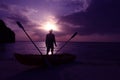 Silhouette kayaking on the beach with man looking at sunset.