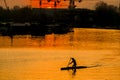 Silhouette of a kayaking man with red sunset over calm river