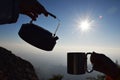 Silhouette kettle and cup at sunrise with mountain background