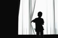 Silhouette of kid opening curtain