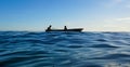 Silhouette of a kid paddling on a boat